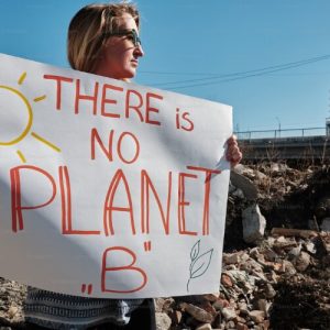 20241027-144931-480-Woman environmental activist with a poster of a landfill behind her.png