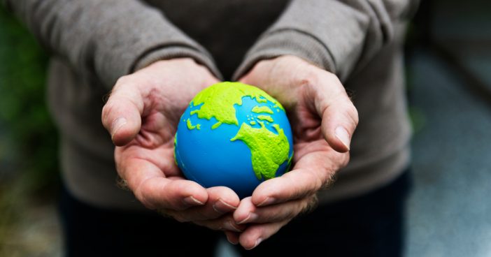 Hands holding a clay globe planet Earth